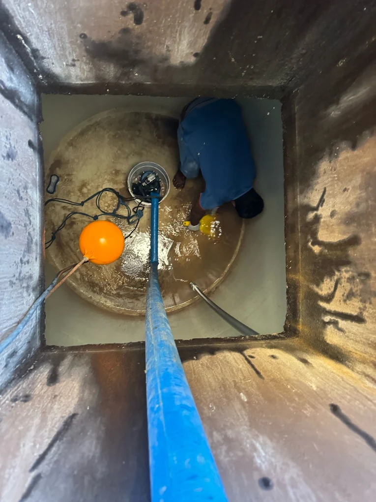 Technician cleaning septic tank from inside near float switch