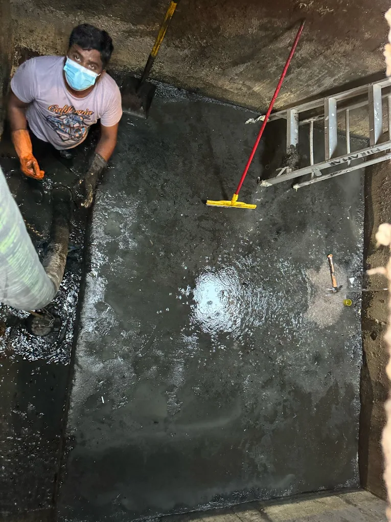 Worker scrubbing floor of sludge tank