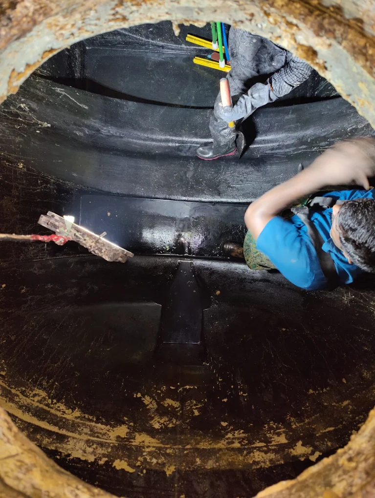 Worker inspecting and cleaning a plastic septic container