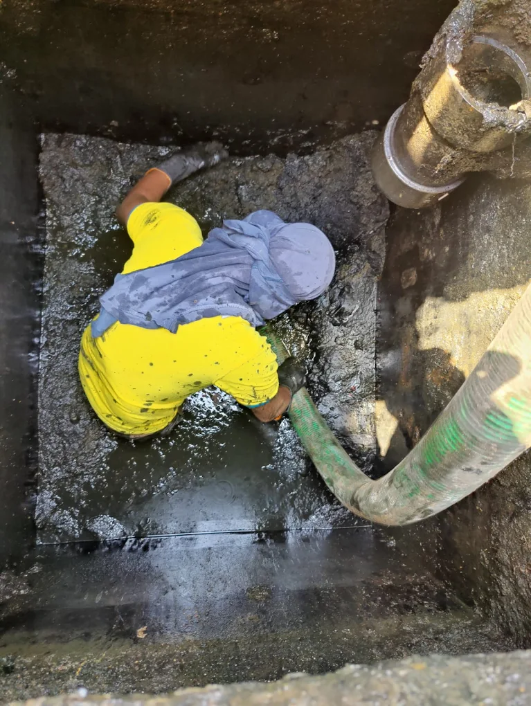 Worker using green suction pipe to pump thick sludge